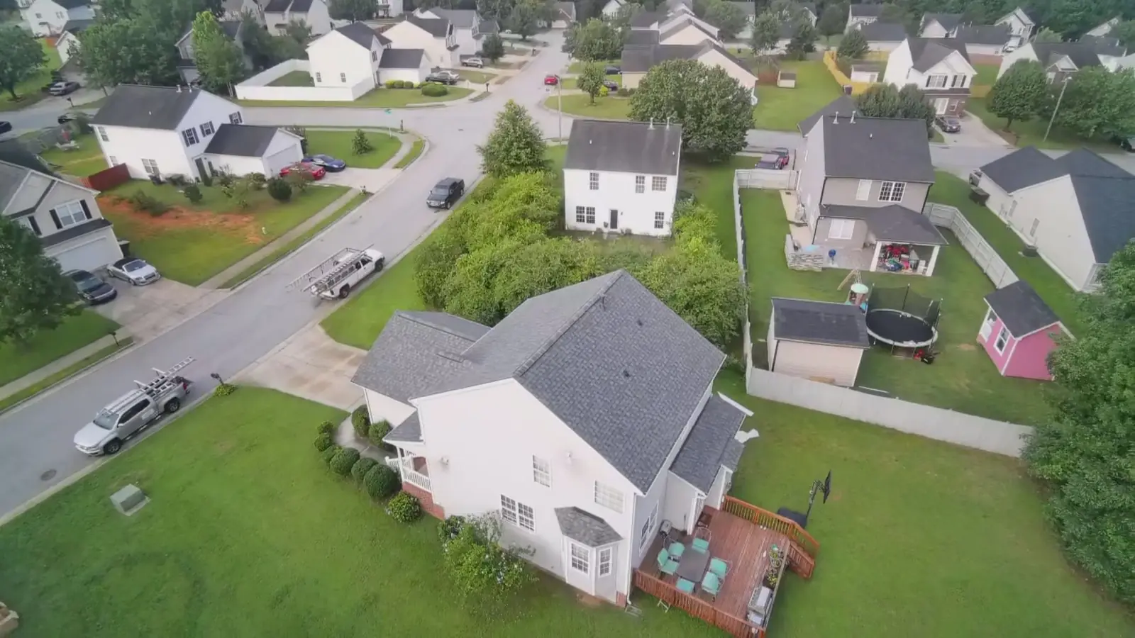 Aerial view of a neighborhood with work trucks parked at the curb